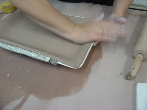 gently pushing the clay down into the mold